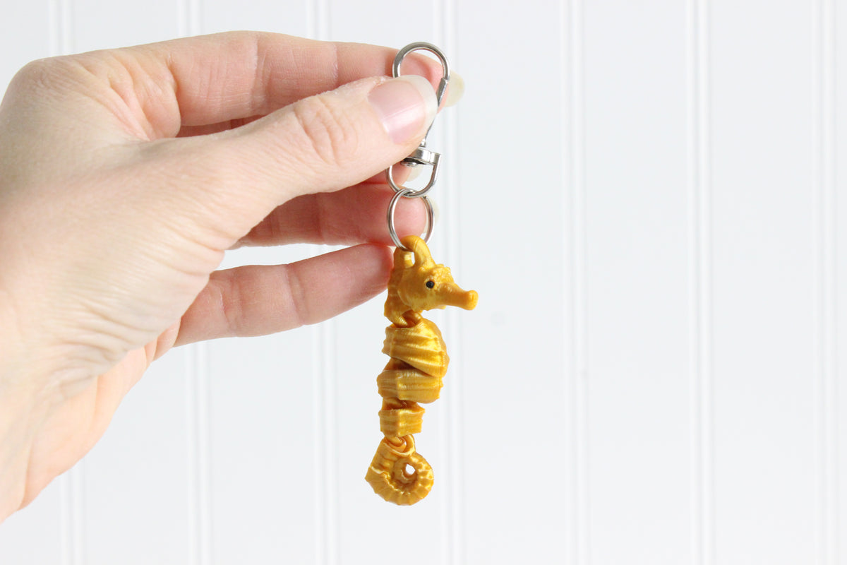 3D-printed seahorse keychain with a silver swivel quick-clip on a white background.