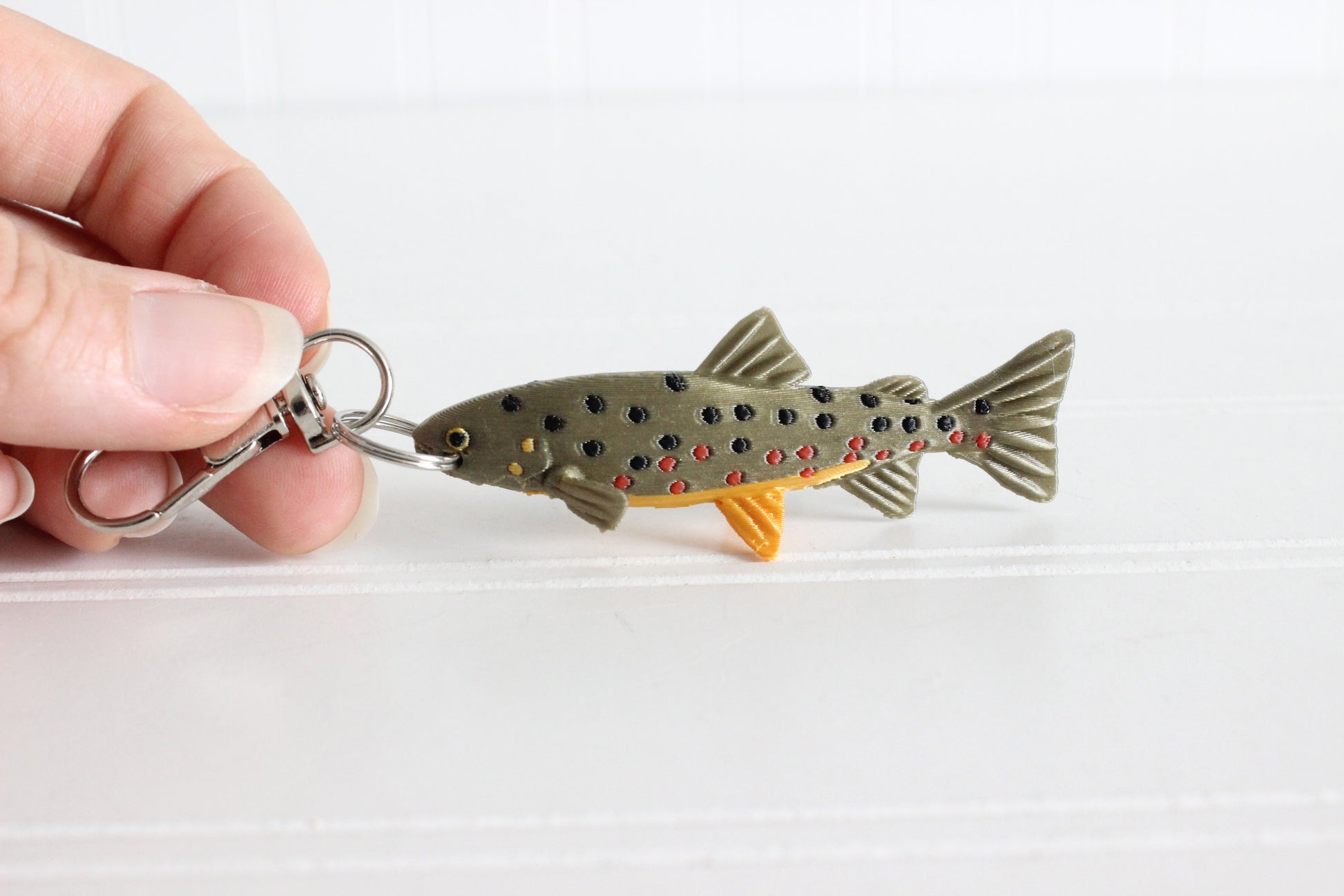 Alternate view of the 3D-printed brown trout with spotted markings keychain showing its sculpted details and segmented design.