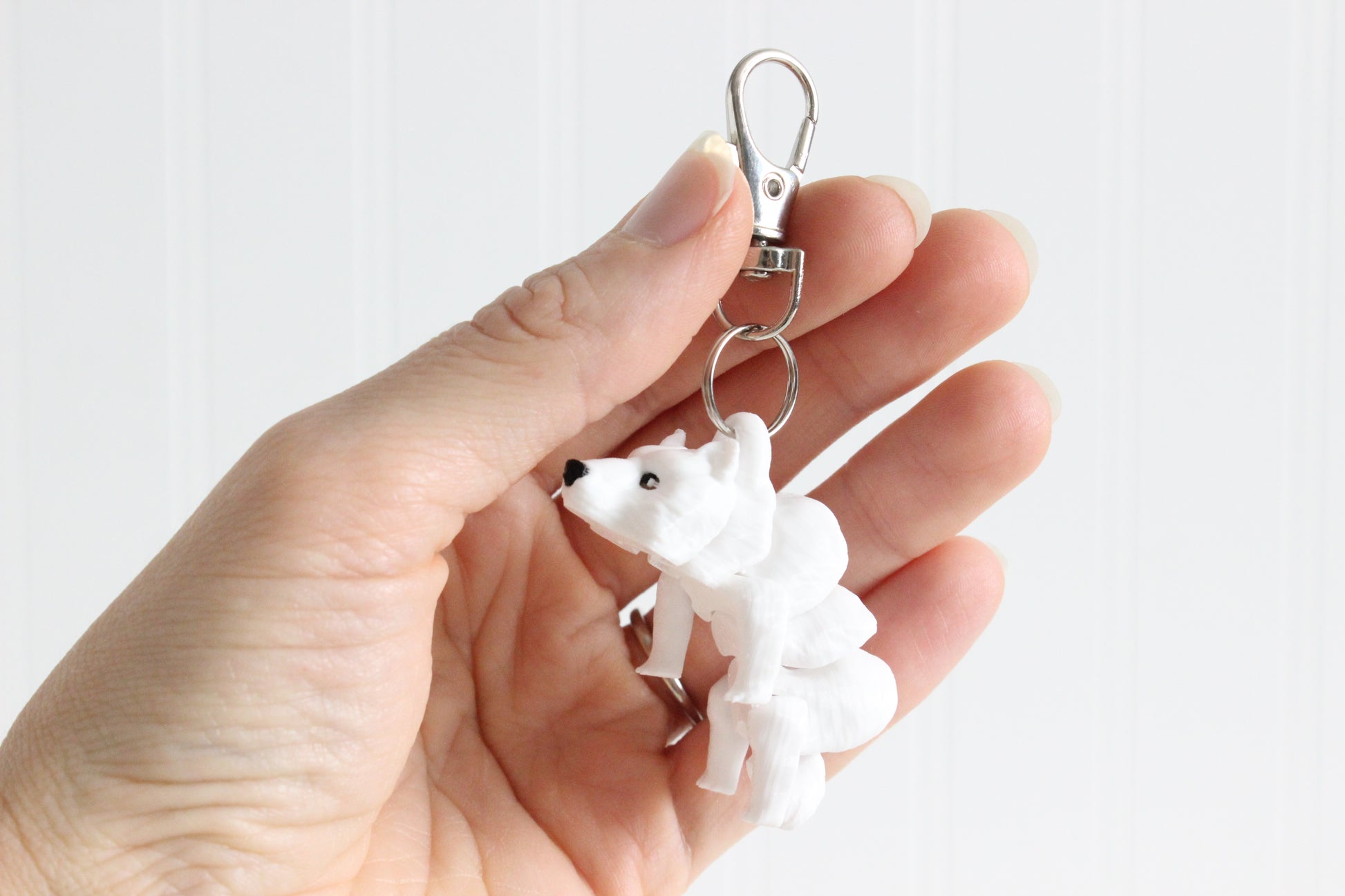 Alternate view of the 3D-printed white polar bear keychain showing its sculpted details and segmented design.