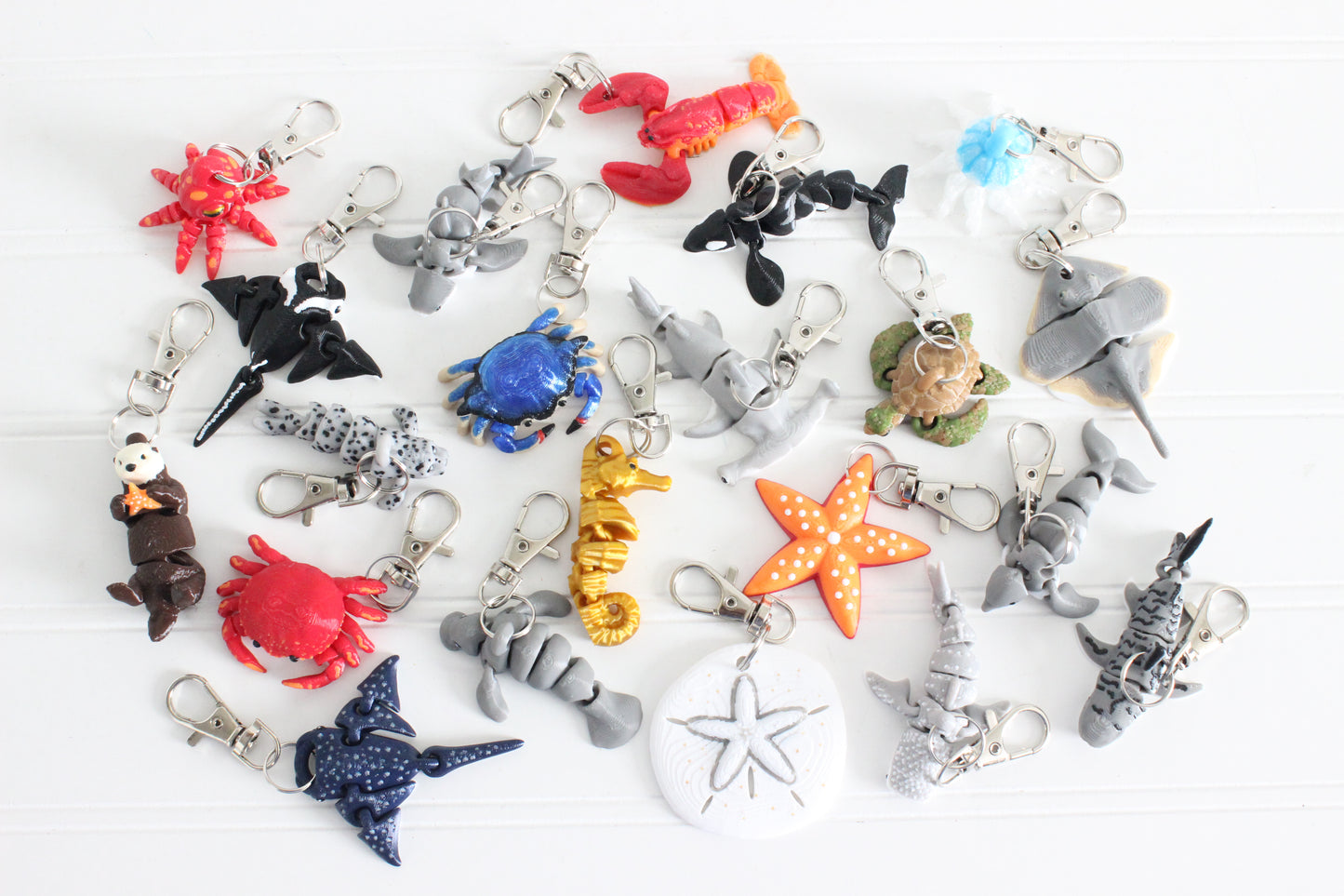 Collection of 3D printed ocean and marine life keychains, including sharks, whales, dolphins, turtles, crabs, lobsters, stingrays, octopuses, starfish, and seahorses, displayed on a white background.